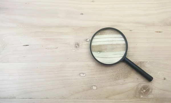 Isolated Object: Detective style Lip Gloss Magnifying Glass, used for viewing small objects, on a wooden background
