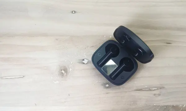 Jakarta, Indonesia - December 22, 2022: Insulated object: black bluetooth headset on white background or insulated wooden base
