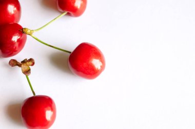 Beyaz arka planda kiraz çilekleri. İzole edilmiş kırmızı kirazlar. Bir sürü kırmızı kiraz ve beyaz üzerine yeşil kuyruk.