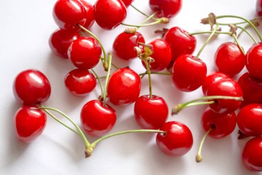 Beyaz arka planda kiraz çilekleri. İzole edilmiş kırmızı kirazlar. Bir sürü kırmızı kiraz ve beyaz üzerine yeşil kuyruk.