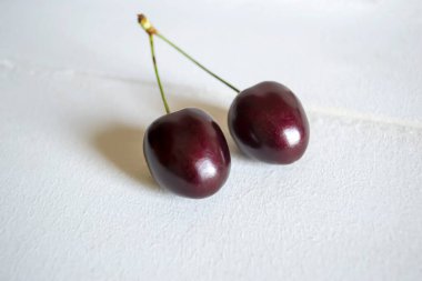 Beyaz arka planda ortak kuyruklu iki kiraz. Beyaz arka planda koyu kirazların yakın plan görüntüsü.