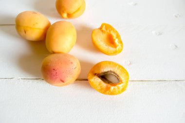 Tahta bir masada taze kayısılar. Yaz meyveleri sulu kayısılardır. Beyaz bir masada büyük turuncu kayısılar..