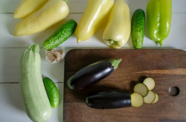 Yaz sebzelerinden taze güveç hazırlıyorum. Beyaz masada patlıcan, dolma biber, sarımsak ve güveç için salatalık var..