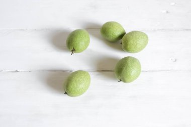 Beyaz arka planda yeşil ceviz meyveleri. Tahta beyaz bir masada ceviz meyveleri var..