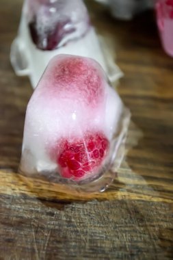 Ahşap arka planda meyveli buz küpleri. Meyveler ve buzlu böğürtlenler. Yazın meyveli olur. Buzlu meyve parçaları..