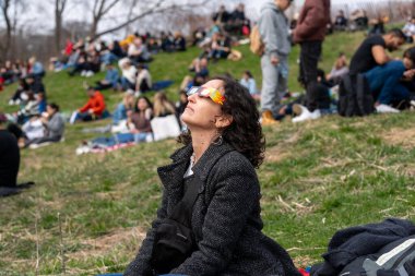 Toronto, Kanada - 8 Nisan 2024: Riverdale Park 'ta kısmi güneş tutulmasının başlangıcını izleyen kadın, özel güneş tutulması gözlüğü takıyor.. 