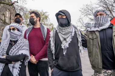 Maskeli Filistinli öğrenciler bir insan zinciri oluşturarak İsrail yanlısı protestocuların Toronto Üniversitesi 'nde King College Circle' ı işgal eden öğrencilerin oluşturduğu kampın önünden geçmelerini engelliyor.. 