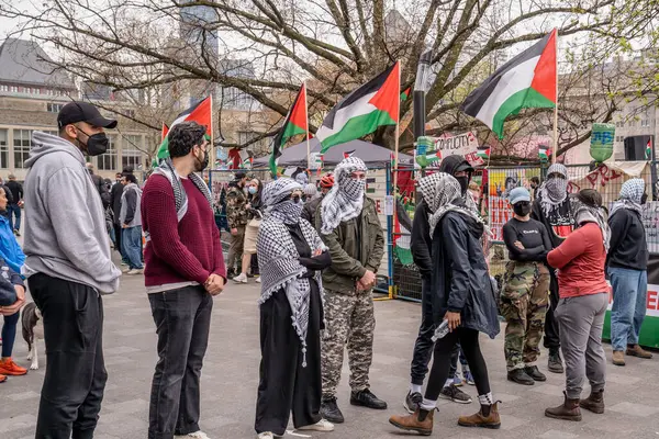 Maskeli Filistinli öğrenciler bir insan zinciri oluşturarak İsrail yanlısı protestocuların Toronto Üniversitesi 'nde King College Circle' ı işgal eden öğrencilerin oluşturduğu kampın önünden geçmelerini engelliyor.. 