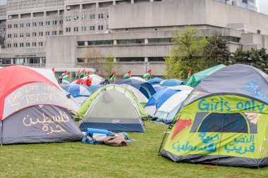 İmza ve sprey boyayla Toronto Üniversitesi 'nde Filistin yanlısı mesajlarla çadır kurmuşlar. Öğrenciler, Filistin yanlısı bir kampla kampüsü işgal ediyor. Filistin hakları için küresel hareketler yansıtıyorlar.