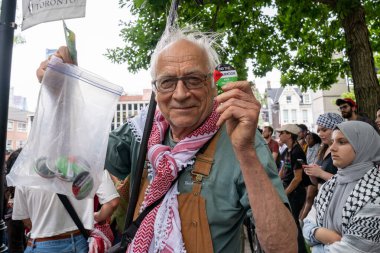 Keffiyeh 'de Pro Filistin' li bir adam Toronto Üniversitesi kampüsündeki King 's College Circle' da düzenlenen mitingde Filistin 'i desteklemek için düğmelere bastı.. 