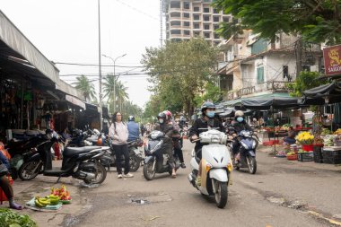 DONG HOI, VİETNAM - 16 Mart 2025: insanlar Dong Hoi, Vietnam 'daki Dong Hoi pazarının dışında motosikletlerine biniyorlar. 