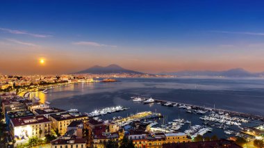 İtalya 'daki Napoli Körfezi manzarası, ön planda marina, arka planda deniz önü ve Vesuvius. Dolunay ufuktan yükseliyor..