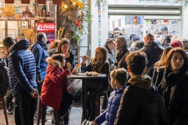 Napoli, İtalya - 11 Aralık 2022: Bir grup insan, bir pizzacının masasında oturarak sokakta yemek alıp yiyor..