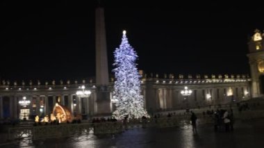 Rome, Italy - December 31, 2022: St. Peter's square decorated with the Christmas tree and the crib illuminated with Christmas lights. The facade of the basilica filmed at night, slow motion footage.