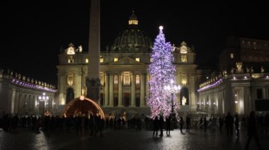 Rome, Italy - December 31, 2022: St. Peter's square decorated with the Christmas tree and the crib illuminated with Christmas lights. The facade of the basilica filmed at night, slow motion footage.