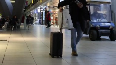 Naples, Italy - January 3, 2023: Inside the central Naples railway station, travelers move around walking with suitcases in the direction of the departure platform.