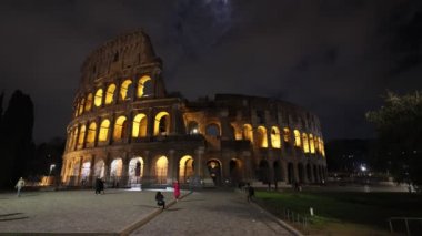 Roma, İtalya - 5 Mart 2023: Roma şehrinin en ünlü anıtı, Kolezyum, geceleri yapay ışıklarla aydınlatılmıştır. Bulutlu gökyüzü.