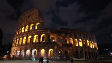 Roma, İtalya - 5 Mart 2023: Roma şehrinin en ünlü anıtı, Kolezyum, geceleri yapay ışıklarla aydınlatılmıştır. Bulutlu gökyüzü.