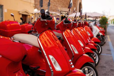 Bir grup kırmızı Vespa scooter park etmiş. Kasabada scooter kiralama.
