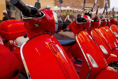 Bir grup kırmızı Vespa scooter park etmiş. Kasabada scooter kiralama.