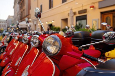 Kırmızı renkli scooterlar park edilmiş. Kasabada scooter kiralama.