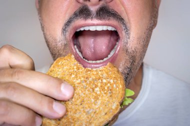 Man eating cheese toast. Close-up, face with gray background.