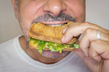 Man eating cheese toast. Close-up, face with gray background.