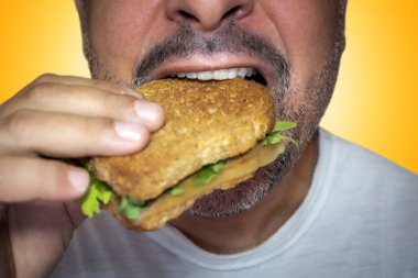 Irresistible craving for junk food. Close-up of a hungry man biting into a cheese toast.