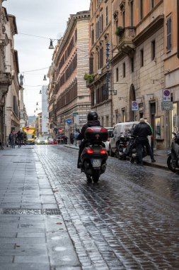 Roma, İtalya - 7 Kasım 2023: Kasvetli bir günde scooterlı bir kişi şehrin tarihi merkezinin sokaklarına çıkar.