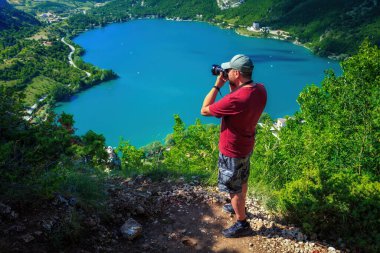 İtalya 'daki Abruzzo Ulusal Parkı' nda ünlü kalp şeklinde bir göl. Yürüyüşçü aşağıdaki göl ile zirveden manzarayı fotoğraflıyor. Scanno Abruzzo Gölü, İtalya.