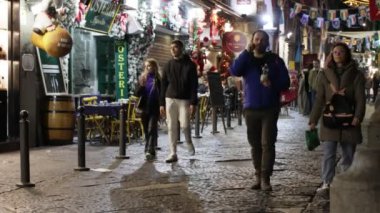 Napoli, İtalya - 21 Aralık 2023: Şehrin tarihi merkezinde, renkli ışıklarla süslenmiş, vatandaşlar akşamları geziniyor ya da Noel tatilinden önce son alışverişlerini yapıyorlar.