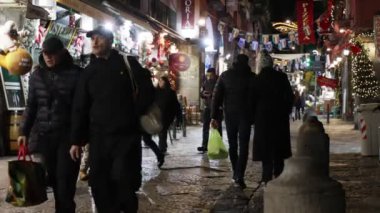 Napoli, İtalya - 21 Aralık 2023: Şehrin tarihi merkezinde, renkli ışıklarla süslenmiş, vatandaşlar akşamları geziniyor ya da Noel tatilinden önce son alışverişlerini yapıyorlar.