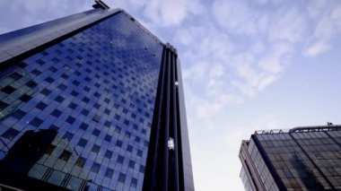 Mavi gökyüzünde akan bulutların yansıtıldığı bir gökdelenin ayna cephesi. Hızlandırılmış zaman, hızlandırılmış zaman.