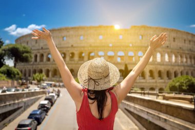 Hasır şapkalı bir kız İtalya 'da Roma' ya turist ziyaretinde, kollarını kaldırarak antik Kolezyum 'un ihtişamının önünde seviniyor ve kollarını kaldırıyor..