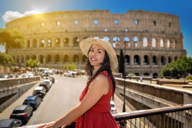 Hasır şapkalı ve kırmızı elbiseli esmer kız İtalya 'daki antik Kolezyum' a hayran. Turist antik Roma 'nın en ünlü anıtını ziyaret eder..