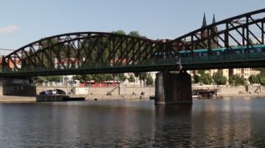 Prag, Çek Cumhuriyeti - 7 Temmuz 2023: Prag şehrinden geçen Vltava Nehri üzerinde seyir. Demirden bir köprünün altından geçen bir tren..
