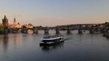 Prag, Çek Cumhuriyeti - 8 Temmuz 2023: Moldova Nehri 'nde seyir, bazı turistlerle dolu tekneler antik Charles Köprüsü' nün kemerlerinden geçerek nehirden geçiyor.