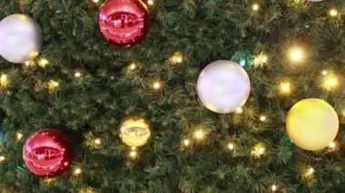 Renkli topları ve yanıp sönen ışıkları olan yeşil bir Noel ağacına yakın plan..