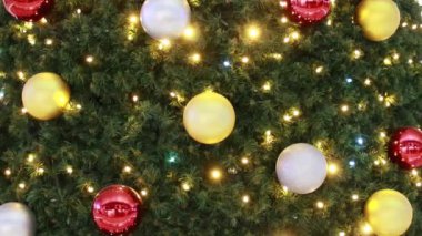 Renkli topları ve yanıp sönen ışıkları olan yeşil bir Noel ağacına yakın plan..