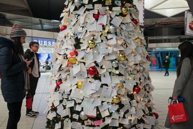 Napoli, İtalya - 11 Aralık 2024: Merkez tren istasyonunda Noel ağacı kuruldu ve yoldan geçen insanlar Noel Baba 'ya dileklerini ve isteklerini herkesin okuyup fotoğraf çekebileceği bir sürü notla ifade ettiler..