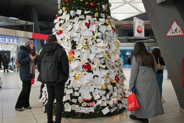 Napoli, İtalya - 11 Aralık 2024: Merkez tren istasyonunda Noel ağacı kuruldu ve yoldan geçen insanlar Noel Baba 'ya dileklerini ve isteklerini herkesin okuyup fotoğraf çekebileceği bir sürü notla ifade ettiler..