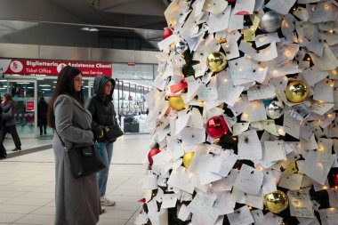 Napoli, İtalya - 11 Aralık 2024: Merkez tren istasyonunda Noel ağacı kuruldu ve yoldan geçen insanlar Noel Baba 'ya dileklerini ve isteklerini herkesin okuyup fotoğraf çekebileceği bir sürü notla ifade ettiler..