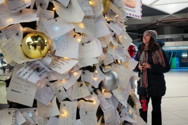 Napoli, İtalya - 11 Aralık 2024: Merkez tren istasyonunda Noel ağacı kuruldu ve yoldan geçen insanlar Noel Baba 'ya dileklerini ve isteklerini herkesin okuyup fotoğraf çekebileceği bir sürü notla ifade ettiler..