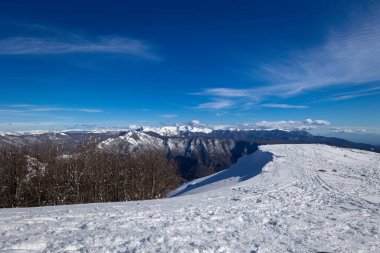 Snowy mountain landscape on a clear winter day, in the background the mountain range and the blue sky. Natural background.