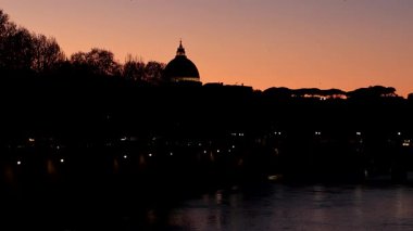 Roma, İtalya - 31 Mart 2025: Tiber Nehri üzerindeki şehirde gün batımı ve arka planda Vatikan 'daki Aziz Peter Bazilikası kubbesi.