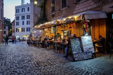 Roma, İtalya - 31 Mart 2025: Trastevere 'de, açık tablolarda ve menülerde sergilenen turistlerin sıkça uğraştığı tipik bir kafe restoranı. Lokantaların rahatı için aydınlatma ve gaz ısıtıcıları.