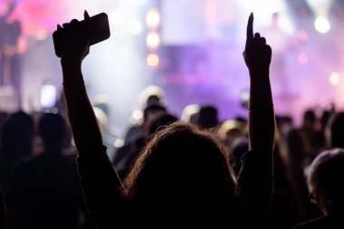 Seyirciler, sahnede sahne alan müzik grubunun konseri sırasında kollarını kaldırarak sevinçten havalara uçuyor..