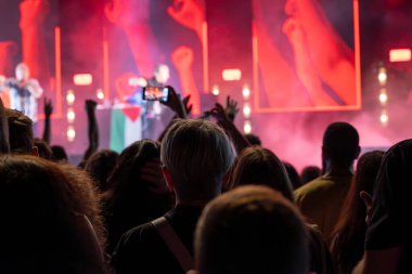 Seyirci, sahnedeki müzik grubunun konserinde akıllı telefonlarıyla video kaydediyor ve fotoğraf çekiyor..