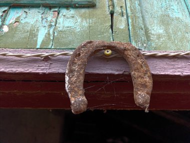 Tahta bir kapının kenarında asılı paslı bir at nalı..