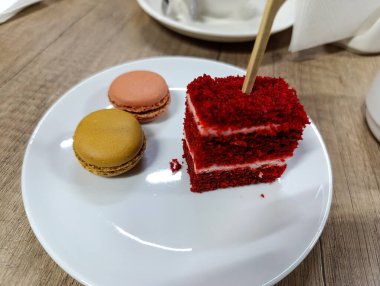 Beyaz bir tabakta kırmızı kadife pasta ve badem kurabiyesi..